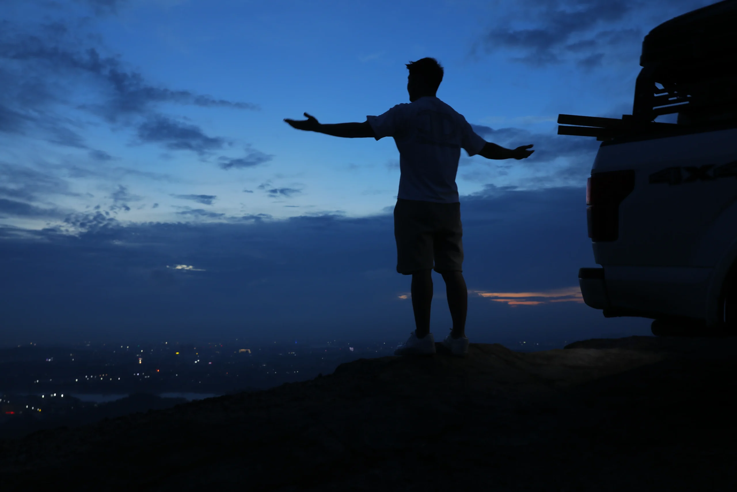 person beside a pickup truck at sunrise during a camping and towing trip
